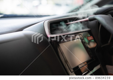 Professional car care service, unrecognizable skillful male worker using a steam machine or heat sterilization inside the car air conditioner system. Steaming a hot air into air conditioner system. 89634159