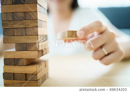 Happy Asian woman enjoy playing a wood block game called wood block tower in the living room during the free time. Happy Asian woman enjoy playing a wood block game called wood block tower in the living room during the free time. 89634203