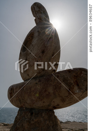 Sculpture symbol made of large pebbles against the blue sky Sculpture symbol made of large pebbles against the blue sky 89634687