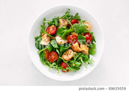 Grilled salmon salad with tomato and salad mix. Top view 89635059