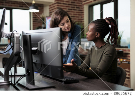 African american digital artist talking with team leader about faulty design software. Multiethnic coworkers in conversation about graphic developing technology and how to improve it. 89635672