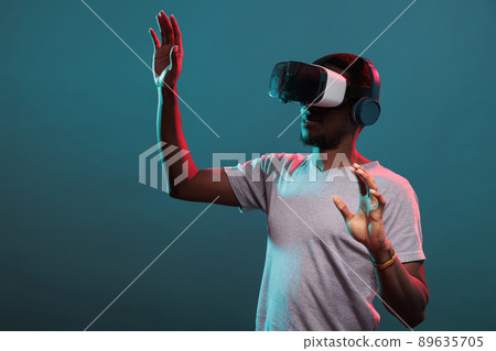 Young adult raising hands to play futuristic game with vr goggles, advertising interactive 3d simulation on glasses technology. Millennial person enjoying virtual reality headset experience. 89635705