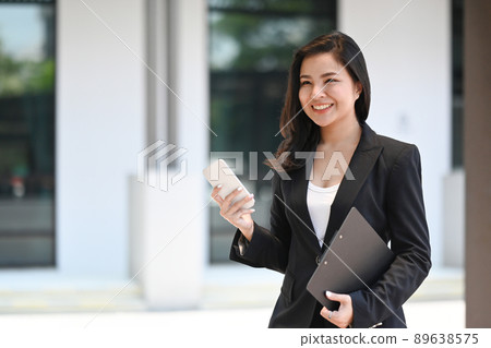 Smart female using smart phone, chatting for business communication while walking at modern office district. Smart female using smart phone, chatting for business communication while walking at modern office district. 89638575