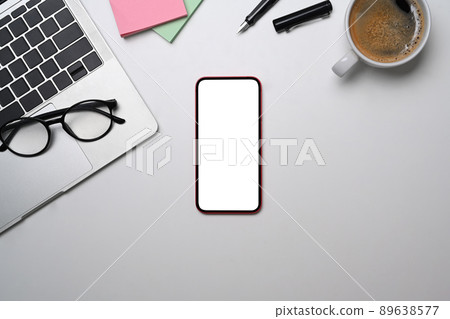 Smart phone, laptop, glasses, coffee cup and sticky notes on white table. Modern workplace, Top view. Smart phone, laptop, glasses, coffee cup and sticky notes on white table. Modern workplace, Top view. 89638577