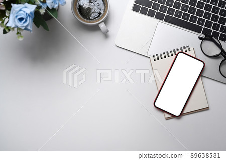 Smart phone, laptop, coffee cup, notepad and glasses on white table. Flat lay, Top view with copy space. Smart phone, laptop, coffee cup, notepad and glasses on white table. Flat lay, Top view with copy space. 89638581