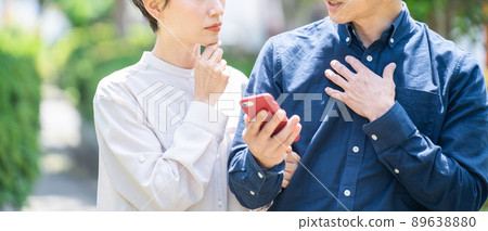 看智能手機的中間夫婦(夫婦,戶外,新鮮綠色,思考,麻煩,問題) 看智能手機的中間夫婦(夫婦,戶外,新鮮綠色,思考,麻煩,問題) 89638880