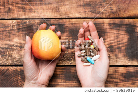Apple natural food and dietary supplements in capsules in female hands wooden background, vitamins Apple natural food and dietary supplements in capsules in female hands wooden background, vitamins 89639019
