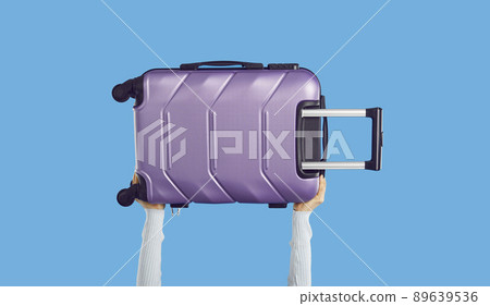 Traveler holding modern purple wheeled suitcase isolated on blue colour background 89639536