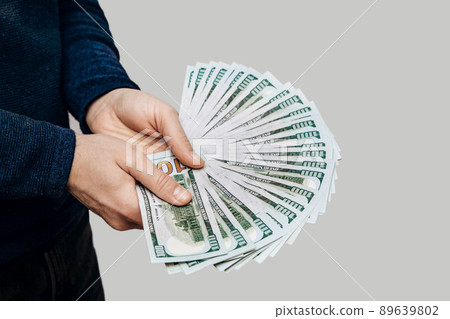 A man holds a fan of 100 dollar bills in his hands 89639802