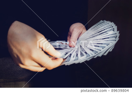 A man holds a fan of 100 dollar bills in his hands. A man counts money A man holds a fan of 100 dollar bills in his hands. A man counts money 89639804