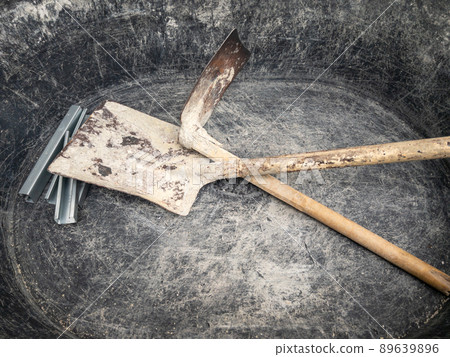 The old plastic bucket with the hoe and shovel for mixing the cement mortar. 89639896