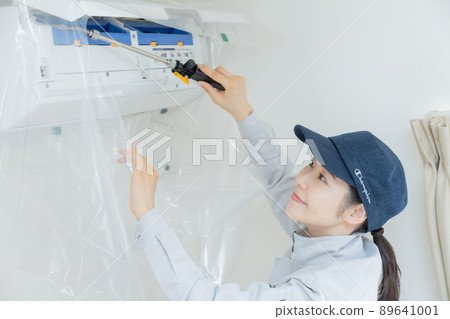 Female staff cleaning the air conditioner Female staff cleaning the air conditioner 89641001