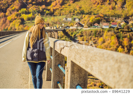 Montenegro. Woman touriste in background of Dzhurdzhevich Bridge Over The River Tara foggy morning. Travel around Montenegro concept. Sights of Montenegro Montenegro. Woman touriste in background of Dzhurdzhevich Bridge Over The River Tara foggy morning. Travel around Montenegro concept. Sights of Montenegro 89641229