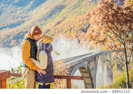 Montenegro. Happy couple man and woman in background of Dzhurdzhevich Bridge Over The River Tara foggy morning. Travel around Montenegro concept. Sights of Montenegro 89641233