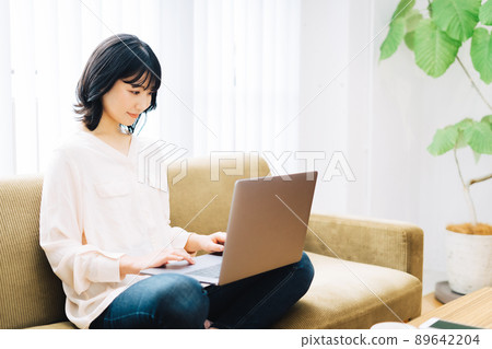 Woman using a computer on the sofa 89642204