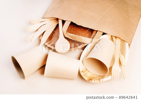 Recycling,eco-friendly concept.Disposable eco cutlery,plates,spoons,knives,forks on a light background.Craft paper bag for food delivery.Copy space.Eco craft paper tableware,cups,fast food containers. 89642641