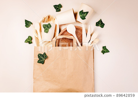 Recycling,eco-friendly concept.Disposable eco cutlery,plates,spoons,knives,forks on a light background.Craft paper bag for food delivery.Copy space.Eco craft paper tableware,cups,fast food containers. 89642859