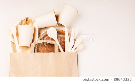 Eco craft paper tableware,cups,fast food containers.Recycling,eco-friendly concept.Disposable eco cutlery,plates,spoons,knives,forks on a light background.Craft paper bag for food delivery.Copy space. 89643323