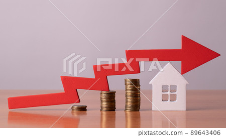 Coins on a table, a red up arrow and house. The concept of the rising price of real estate 89643406