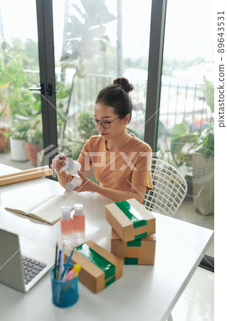 Woman online store preparing a parcel at workplace. Woman online store preparing a parcel at workplace. 89643531