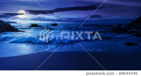 empty beach at night. beautiful landscape at the sea. waves washing the sand and stones on the shore. clouds glowing in full moon light. calm summer vacation and travel destination concept empty beach at night. beautiful landscape at the sea. waves washing the sand and stones on the shore. clouds glowing in full moon light. calm summer vacation and travel destination concept 89644346