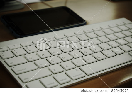 Close-up shot keyboard of computer with black mobile phone on wooden desktop, workplace and equipment for creative and designer. Close-up shot keyboard of computer with black mobile phone on wooden desktop, workplace and equipment for creative and designer. 89645075