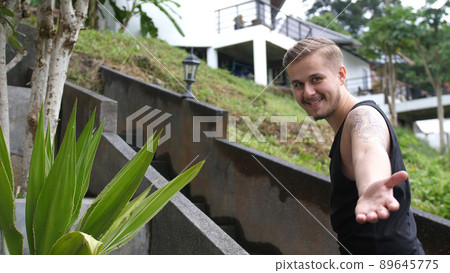 Young man inviting someone to come on up stair in tropical island 89645775