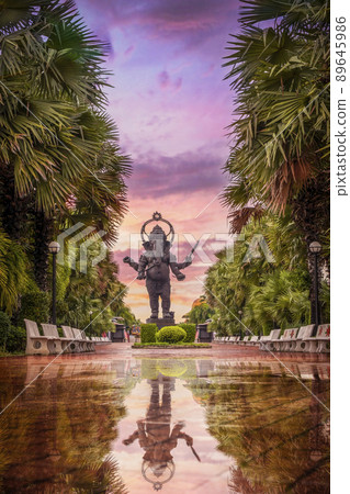 A large bronze statue of Ganesha is god of Hindu which one of the best-known and most worshipped deities standing in the park at twilight time and there is a reflection of water on ground after rain. A large bronze statue of Ganesha is god of Hindu which one of the best-known and most worshipped deities standing in the park at twilight time and there is a reflection of water on ground after rain. 89645986