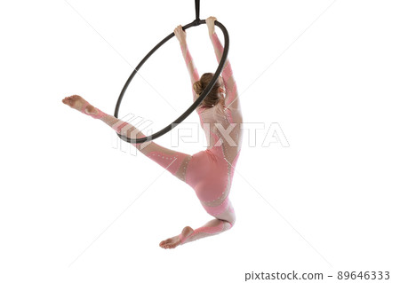 Portrait of young sportive girl, air gymnast performing on hoop isolated over white studio background. Strong hands Portrait of young sportive girl, air gymnast performing on hoop isolated over white studio background. Strong hands 89646333