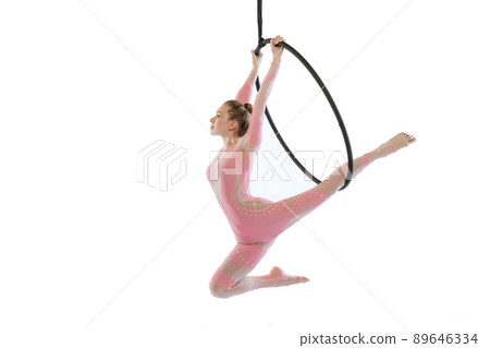 Portrait of young sportive girl, air gymnast performing on hoop isolated over white studio background. Flying high 89646334