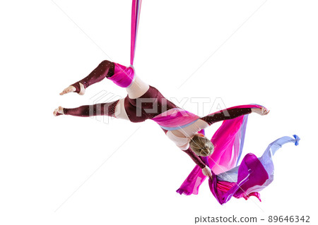 Portrait of young woman, air gymnast training, performing isolated over white studio background. Fascinating performance Portrait of young woman, air gymnast training, performing isolated over white studio background. Fascinating performance 89646342