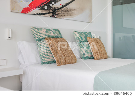 Beautiful and comfortable pillows in bedroom of a hotel with abstract picture above the bed. Beautiful and comfortable pillows in bedroom of a hotel with abstract picture above the bed. 89646400