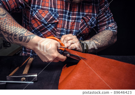 Man working with leather using crafting scissors Man working with leather using crafting scissors 89646423