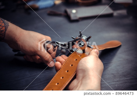 Craftsman performs leather working for a new product in his tanning shop Craftsman performs leather working for a new product in his tanning shop 89646473