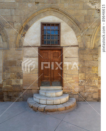 Old wooden door and window framed by arched bricks stone wall at the courtyard of al Razzaz historic house, Old Cairo, Egypt 89646615