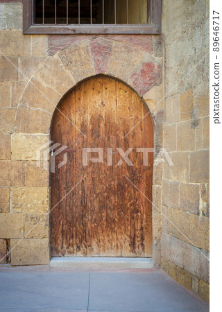 Old wooden door framed by arched bricks stone wall, Darb al Ahmar district, Old Cairo, Egypt 89646717