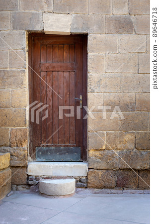Old wooden door framed by bricks stone wall, Darb al Ahmar district, Old Cairo, Egypt 89646718
