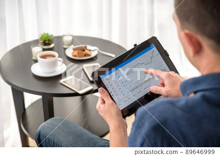 Man trading digital currencies online while relaxing by the cup of coffee in expencive hotel room 89646999