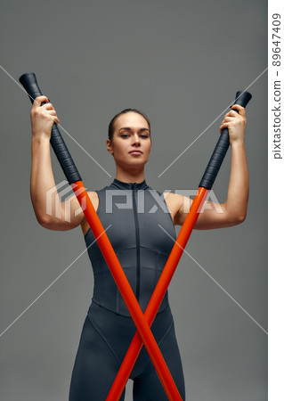 beautiful girl in sports uniform is training kung fu in the studio, fighter athlete, practicing martial arts with a stick beautiful girl in sports uniform is training kung fu in the studio, fighter athlete, practicing martial arts with a stick 89647409