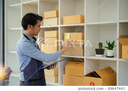 Young attractive asian owner startup business look at camera work happy with box at home prepare parcel delivery in sme supply chain, procurement, omnichannel or coronavirus quarantine concept 89647441