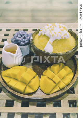Bingsu or shaved ice dessert topped with coconut fresh cream and mango sliced served with sticky rice and mango sauce, sweet dessert in Korean style. Bingsu or shaved ice dessert topped with coconut fresh cream and mango sliced served with sticky rice and mango sauce, sweet dessert in Korean style. 89647490