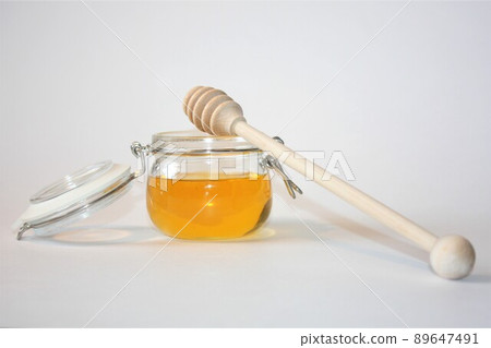 A jar of honey with a wooden spoon, close up. A jar of honey with a wooden spoon, close up. 89647491
