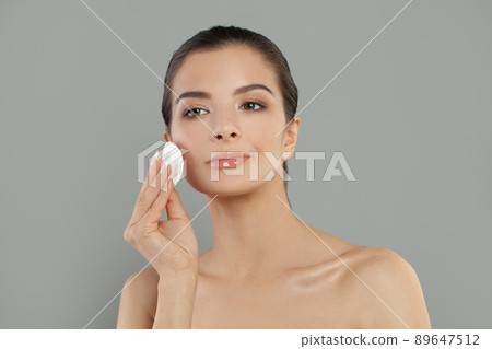 Beautiful brunette woman holding cotton disk pad removing makeup facial skin Beautiful brunette woman holding cotton disk pad removing makeup facial skin 89647512