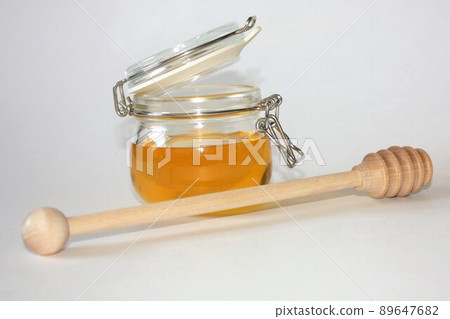 A jar of honey and a special wooden spoon on a white background. Close-up A jar of honey and a special wooden spoon on a white background. Close-up 89647682