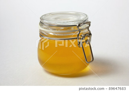 Isolated closed glass jar of honey on a white background. Close-up. Isolated closed glass jar of honey on a white background. Close-up. 89647683