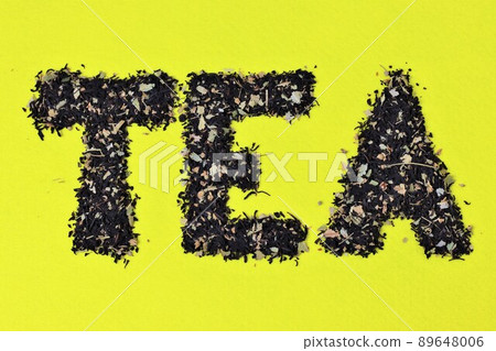 The word tea from black leaf tea on a yellow background. The word tea from black leaf tea on a yellow background. 89648006