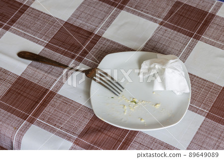 empty white dish with leftovers of eaten food, crumpled table-napkin and steel fork empty white dish with leftovers of eaten food, crumpled table-napkin and steel fork 89649089