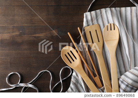 Apron with kitchen utensil on wooden background Apron with kitchen utensil on wooden background 89649868