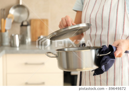 Woman in apron holds metal pot, space for text 89649872