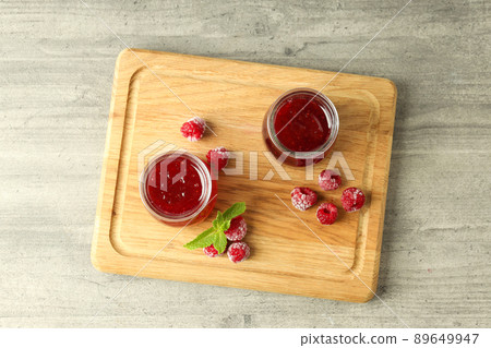 Glass jars of raspberry jam with ingredients on wooden board Glass jars of raspberry jam with ingredients on wooden board 89649947